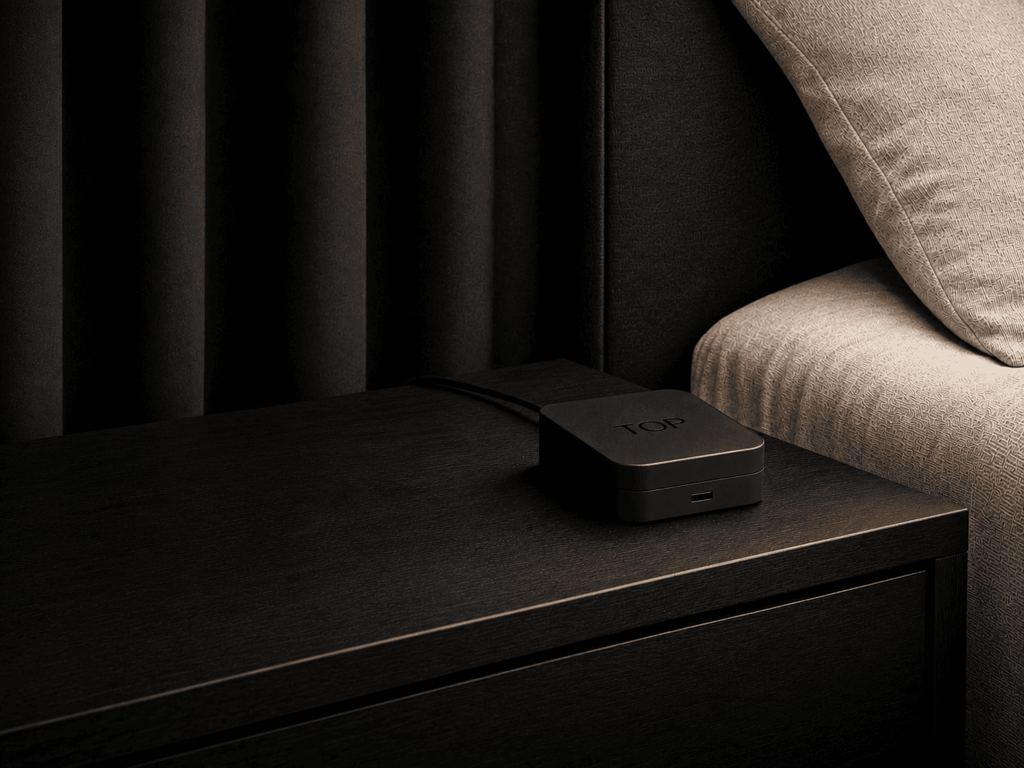 A TOP device on the nightstand of a dark bedroom